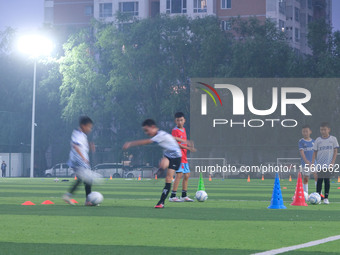 Children practice soccer at the evening soccer field of Capital Sport University in Beijing, China, on September 9, 2024. (