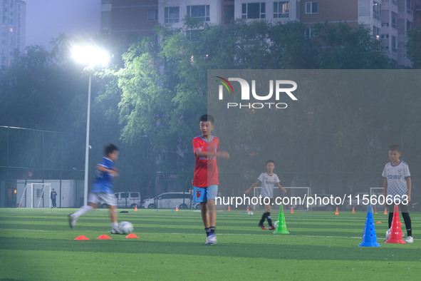 Children practice soccer at the evening soccer field of Capital Sport University in Beijing, China, on September 9, 2024. 