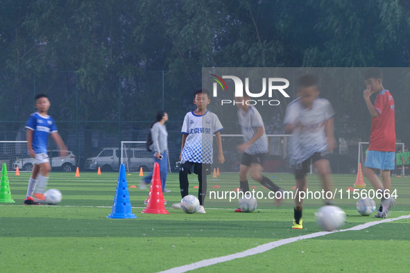 Children practice soccer at the evening soccer field of Capital Sport University in Beijing, China, on September 9, 2024. 