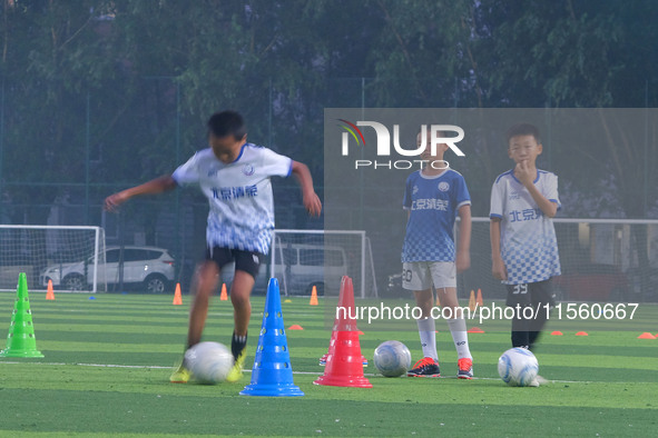 Children practice soccer at the evening soccer field of Capital Sport University in Beijing, China, on September 9, 2024. 