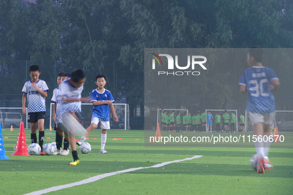 Children practice soccer at the evening soccer field of Capital Sport University in Beijing, China, on September 9, 2024. 