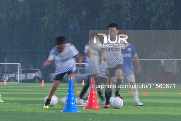 Children practice soccer at the evening soccer field of Capital Sport University in Beijing, China, on September 9, 2024. 