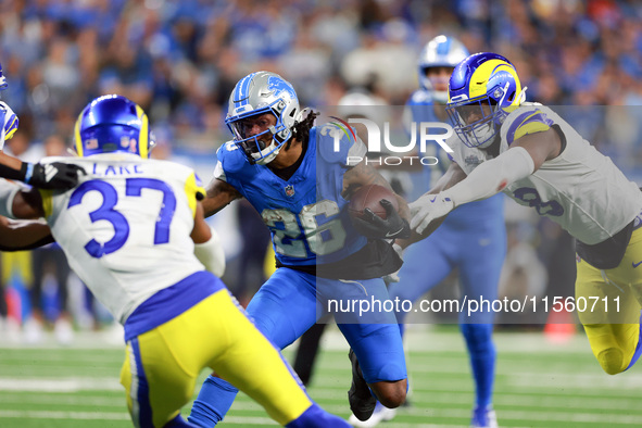 DETROIT,MICHIGAN-SEPTEMBER 8:  Running back Jahmyr Gibbs (26) of the Detroit Lions carries the ball under the pressure of safety Quentin Lak...