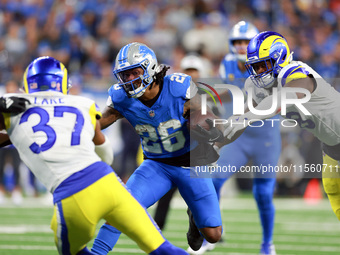 DETROIT,MICHIGAN-SEPTEMBER 8:  Running back Jahmyr Gibbs (26) of the Detroit Lions carries the ball under the pressure of safety Quentin Lak...