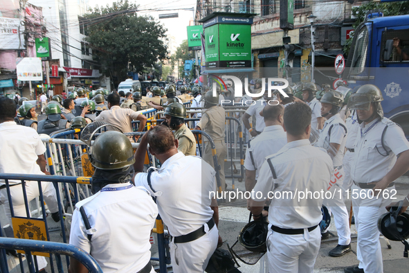 Police officials stand guard while Left Party members shout slogans during a protest rally towards Kolkata Police Headquarters, Lalbazar, to...