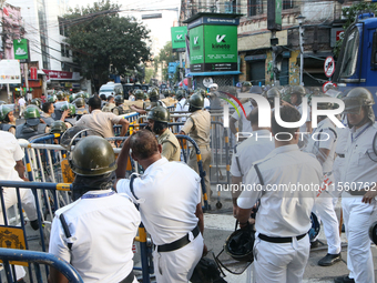 Police officials stand guard while Left Party members shout slogans during a protest rally towards Kolkata Police Headquarters, Lalbazar, to...