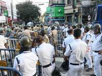 Police officials stand guard while Left Party members shout slogans during a protest rally towards Kolkata Police Headquarters, Lalbazar, to...