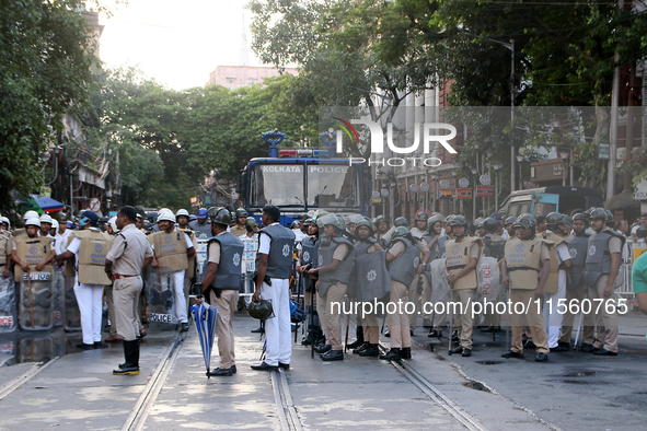 Police officials stand guard while Left Party members shout slogans during a protest rally towards Kolkata Police Headquarters, Lalbazar, to...