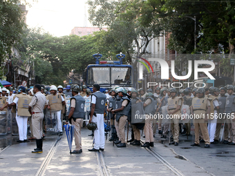 Police officials stand guard while Left Party members shout slogans during a protest rally towards Kolkata Police Headquarters, Lalbazar, to...