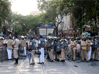 Police officials stand guard while Left Party members shout slogans during a protest rally towards Kolkata Police Headquarters, Lalbazar, to...