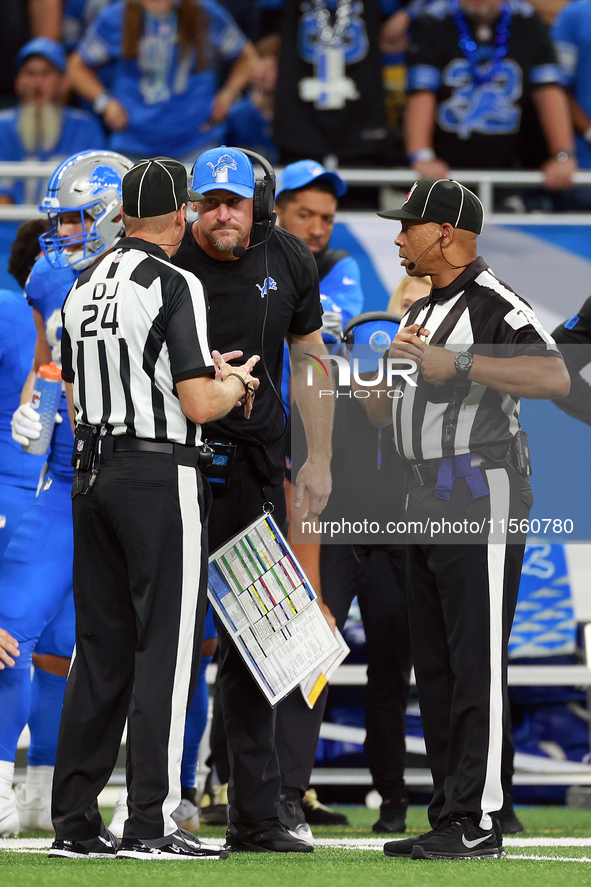 DETROIT,MICHIGAN-SEPTEMBER 8:   Down judge David Oliver (24) and back judge Greg Steed (12)  talk with head coach Dan Campbell during a game...