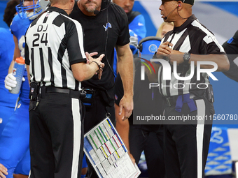 DETROIT,MICHIGAN-SEPTEMBER 8:   Down judge David Oliver (24) and back judge Greg Steed (12)  talk with head coach Dan Campbell during a game...