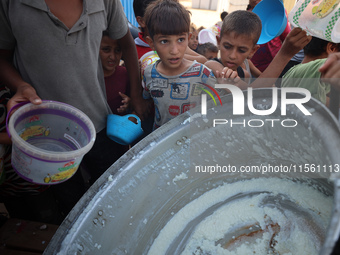 Displaced Palestinian children wait at a food distribution point in Deir el-Balah, Gaza Strip, on September 9, 2024, amid the ongoing confli...