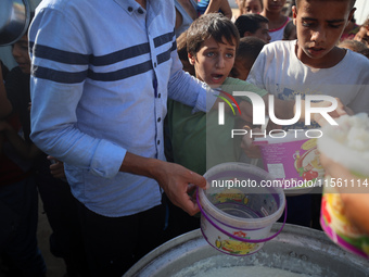 Displaced Palestinian children wait at a food distribution point in Deir el-Balah, Gaza Strip, on September 9, 2024, amid the ongoing confli...