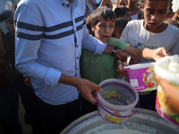 Displaced Palestinian children wait at a food distribution point in Deir el-Balah, Gaza Strip, on September 9, 2024, amid the ongoing confli...