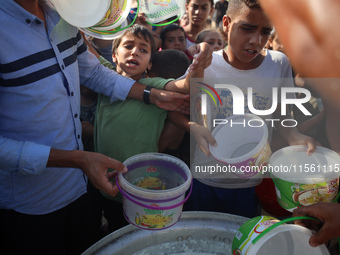 Displaced Palestinian children wait at a food distribution point in Deir el-Balah, Gaza Strip, on September 9, 2024, amid the ongoing confli...