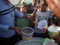 Displaced Palestinian children wait at a food distribution point in Deir el-Balah, Gaza Strip, on September 9, 2024, amid the ongoing confli...