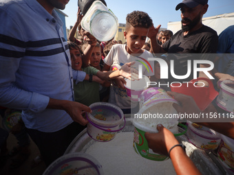 Displaced Palestinian children wait at a food distribution point in Deir el-Balah, Gaza Strip, on September 9, 2024, amid the ongoing confli...