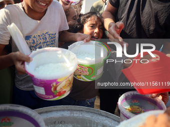 Displaced Palestinian children wait at a food distribution point in Deir el-Balah, Gaza Strip, on September 9, 2024, amid the ongoing confli...