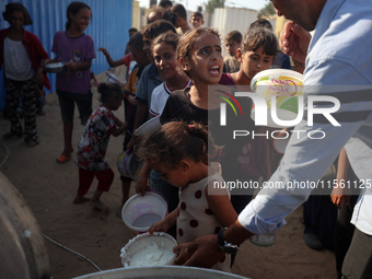 Displaced Palestinian children wait at a food distribution point in Deir el-Balah, Gaza Strip, on September 9, 2024, amid the ongoing confli...