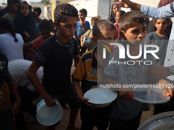 Displaced Palestinian children wait at a food distribution point in Deir el-Balah, Gaza Strip, on September 9, 2024, amid the ongoing confli...