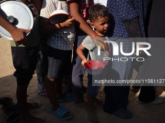 Displaced Palestinian children wait at a food distribution point in Deir el-Balah, Gaza Strip, on September 9, 2024, amid the ongoing confli...