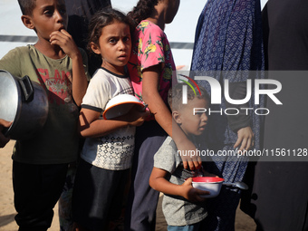 Displaced Palestinian children wait at a food distribution point in Deir el-Balah, Gaza Strip, on September 9, 2024, amid the ongoing confli...