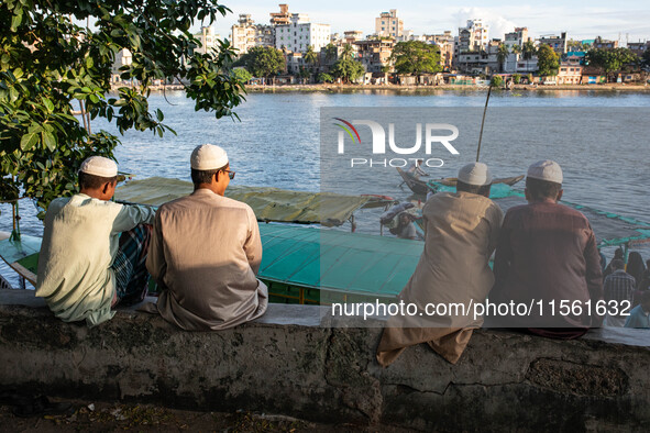 Muslim religious people sit on a bench by the riverside in Dhaka, Bangladesh, on September 9, 2024. 