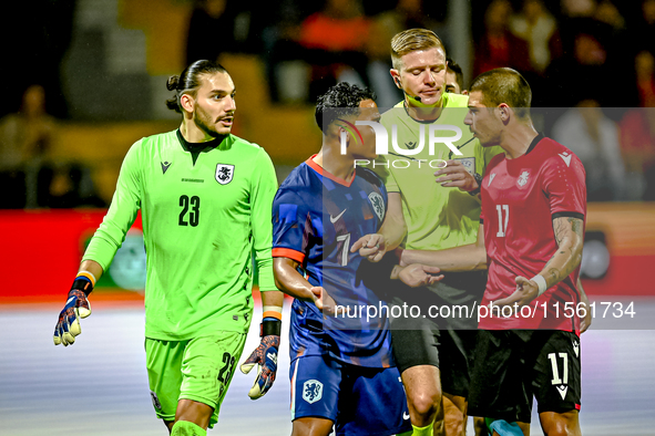 Georgia goalkeeper Luka Kharatishvili, Netherlands player Million Manhoef, referee Robert Schroder, and Georgia player Levan Osikmashvili du...