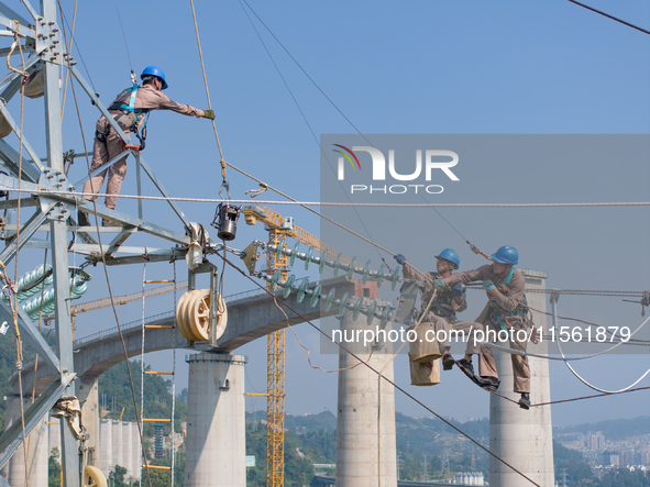 Electric power employees work on a steel tower near the Shuigang Railway in Xikouping village, Yichang city, Central China's Hubei province,...