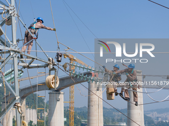 Electric power employees work on a steel tower near the Shuigang Railway in Xikouping village, Yichang city, Central China's Hubei province,...