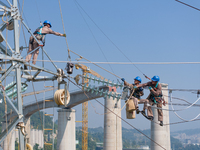 Electric power employees work on a steel tower near the Shuigang Railway in Xikouping village, Yichang city, Central China's Hubei province,...