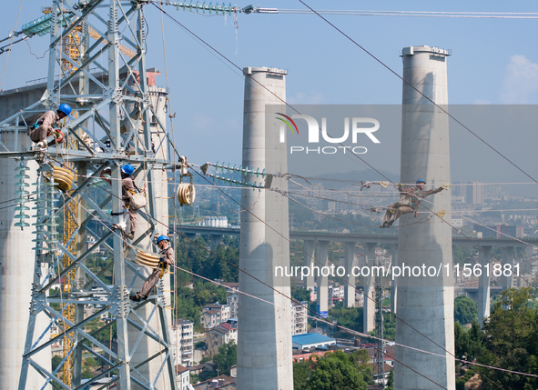 Electric power employees work on a steel tower near the Shuigang Railway in Xikouping village, Yichang city, Central China's Hubei province,...