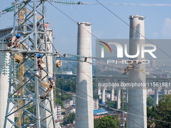 Electric power employees work on a steel tower near the Shuigang Railway in Xikouping village, Yichang city, Central China's Hubei province,...