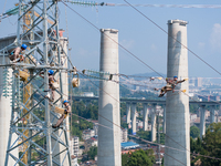 Electric power employees work on a steel tower near the Shuigang Railway in Xikouping village, Yichang city, Central China's Hubei province,...