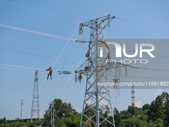 Electric power employees work on a steel tower near the Shuigang Railway in Xikouping village, Yichang city, Central China's Hubei province,...