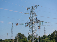 Electric power employees work on a steel tower near the Shuigang Railway in Xikouping village, Yichang city, Central China's Hubei province,...