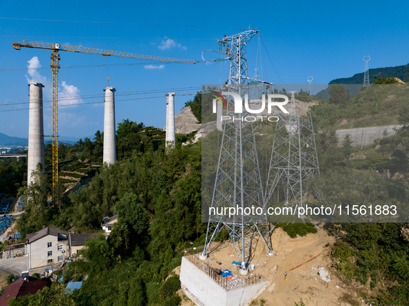 Electric power employees work on a steel tower near the Shuigang Railway in Xikouping village, Yichang city, Central China's Hubei province,...