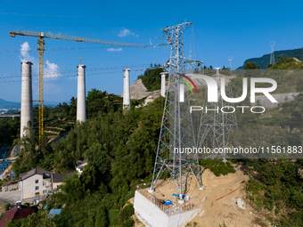 Electric power employees work on a steel tower near the Shuigang Railway in Xikouping village, Yichang city, Central China's Hubei province,...