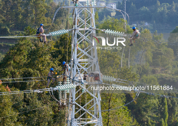 Electric power employees work on a steel tower near the Shuigang Railway in Xikouping village, Yichang city, Central China's Hubei province,...