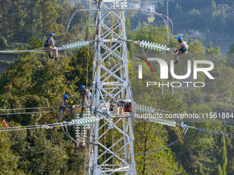 Electric power employees work on a steel tower near the Shuigang Railway in Xikouping village, Yichang city, Central China's Hubei province,...