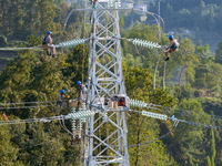 Electric power employees work on a steel tower near the Shuigang Railway in Xikouping village, Yichang city, Central China's Hubei province,...