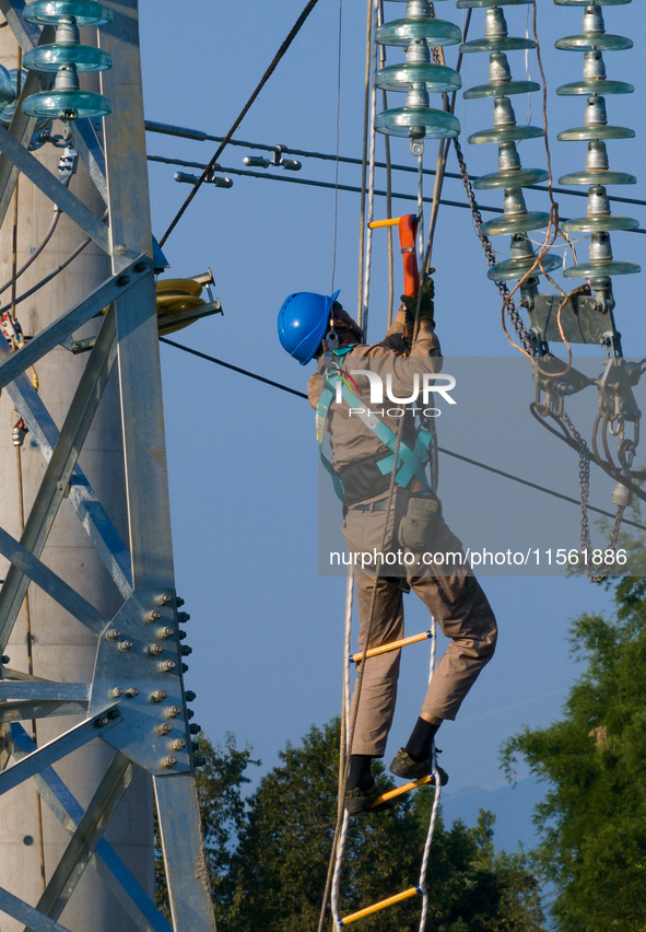 Electric power employees work on a steel tower near the Shuigang Railway in Xikouping village, Yichang city, Central China's Hubei province,...