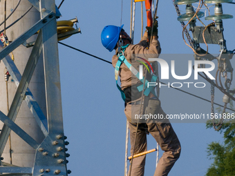 Electric power employees work on a steel tower near the Shuigang Railway in Xikouping village, Yichang city, Central China's Hubei province,...