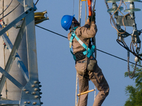 Electric power employees work on a steel tower near the Shuigang Railway in Xikouping village, Yichang city, Central China's Hubei province,...