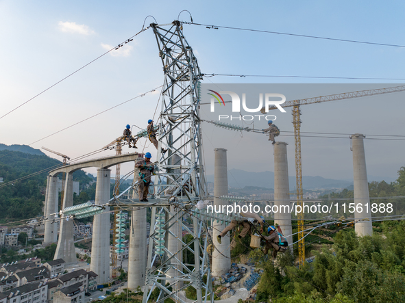 Electric power employees work on a steel tower near the Shuigang Railway in Xikouping village, Yichang city, Central China's Hubei province,...