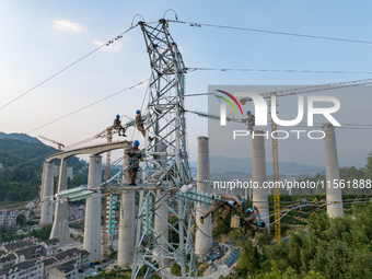 Electric power employees work on a steel tower near the Shuigang Railway in Xikouping village, Yichang city, Central China's Hubei province,...