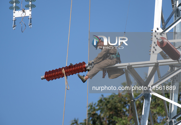 Electric power employees work on a steel tower near the Shuigang Railway in Xikouping village, Yichang city, Central China's Hubei province,...