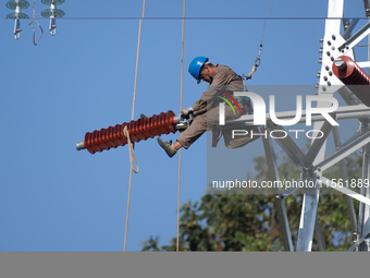 Electric power employees work on a steel tower near the Shuigang Railway in Xikouping village, Yichang city, Central China's Hubei province,...