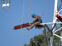 Electric power employees work on a steel tower near the Shuigang Railway in Xikouping village, Yichang city, Central China's Hubei province,...